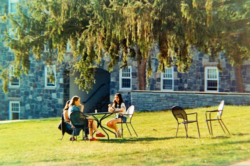 Students eating ice cream at a metal cafe table on the East Lawn